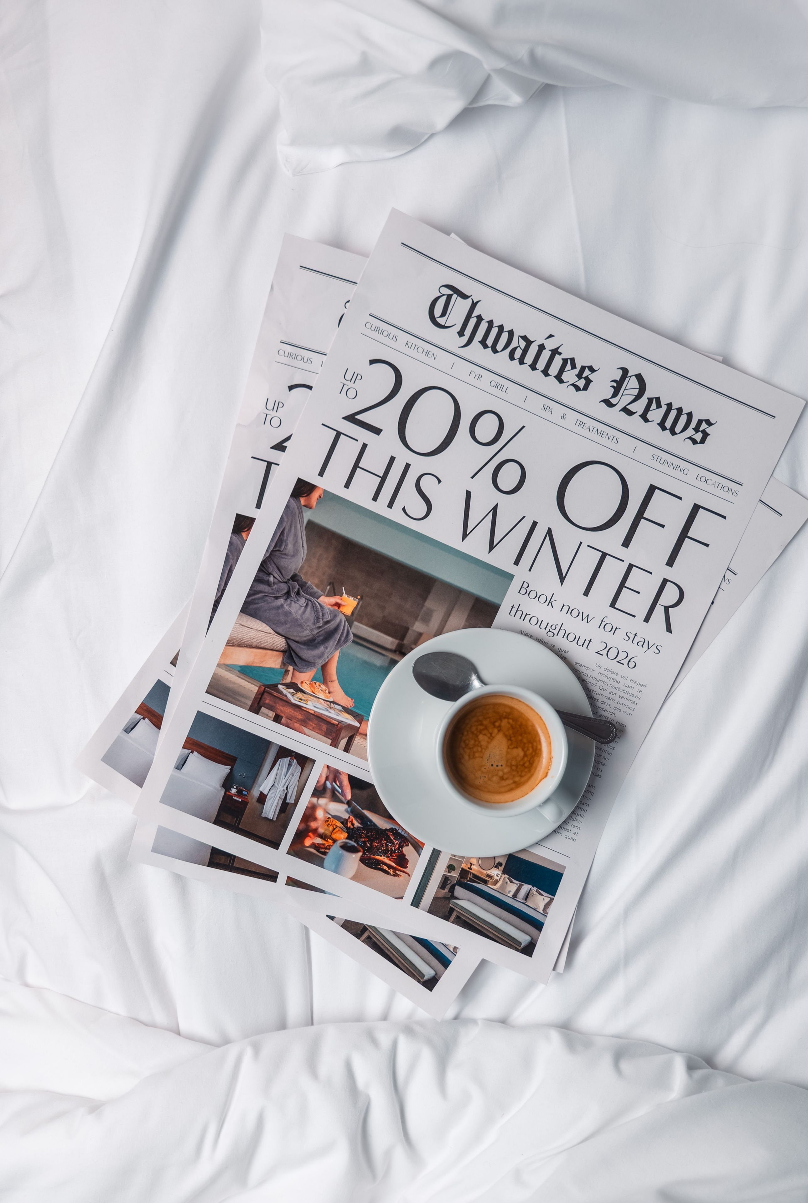 Magazine on a hotel bed with a cup of coffee that reads "Up to 20% off this winter"